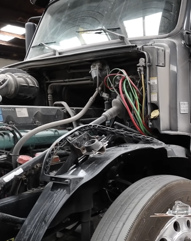 Semi truck engine compartment showing wiring and electrical repairs